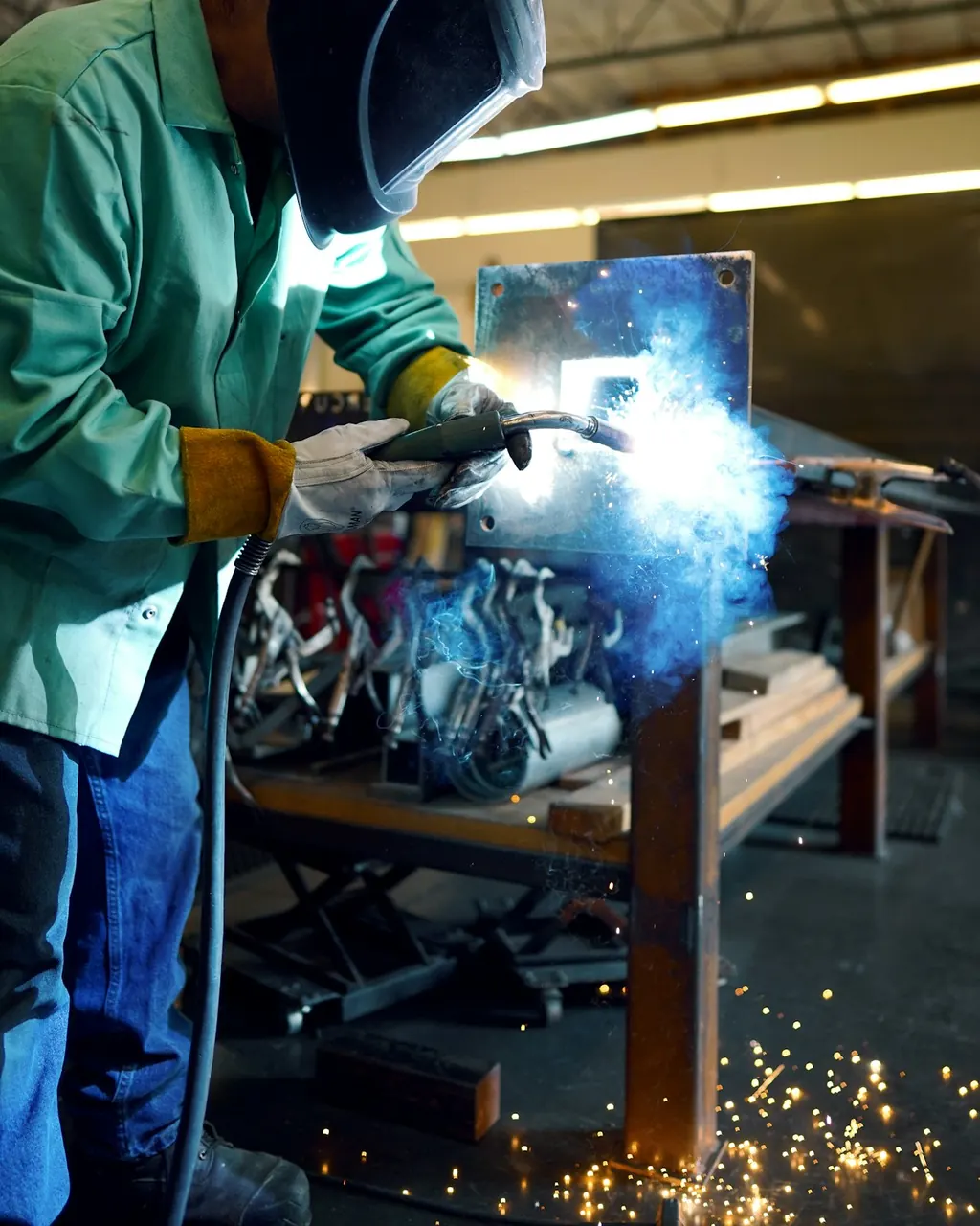 Schweißer in Schutzkleidung bei der Arbeit in der Werkstatt